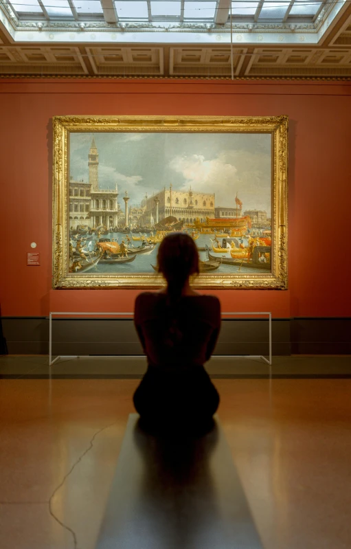 there is a woman sitting on the floor looking at a painting