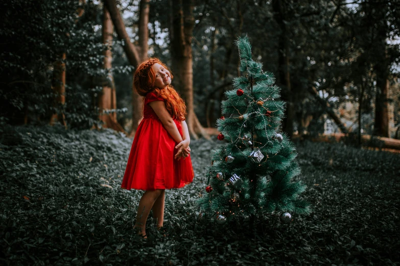 a beautiful woman dressed in red posing near a christmas tree