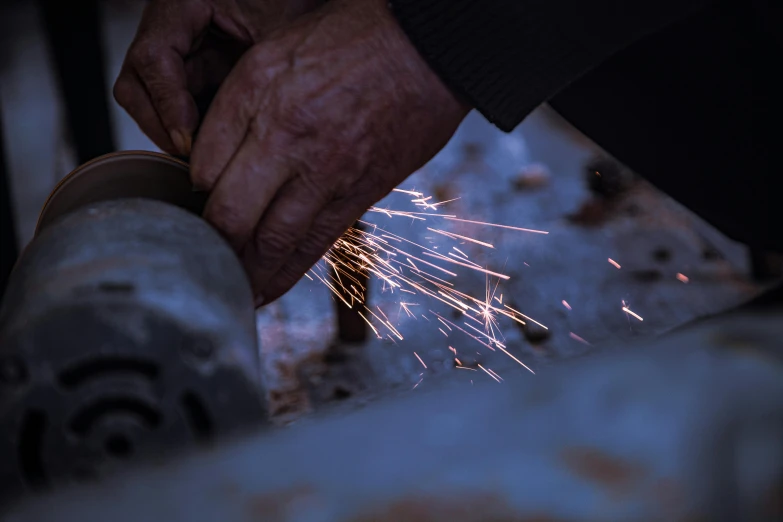 person operating electric grinding machine with sparks in hand