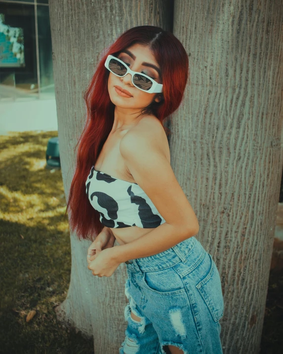 a woman with red hair standing next to a tree