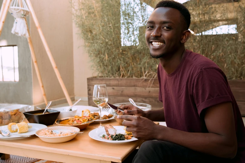 a man sits at a table with a bowl of salad and glass of wine