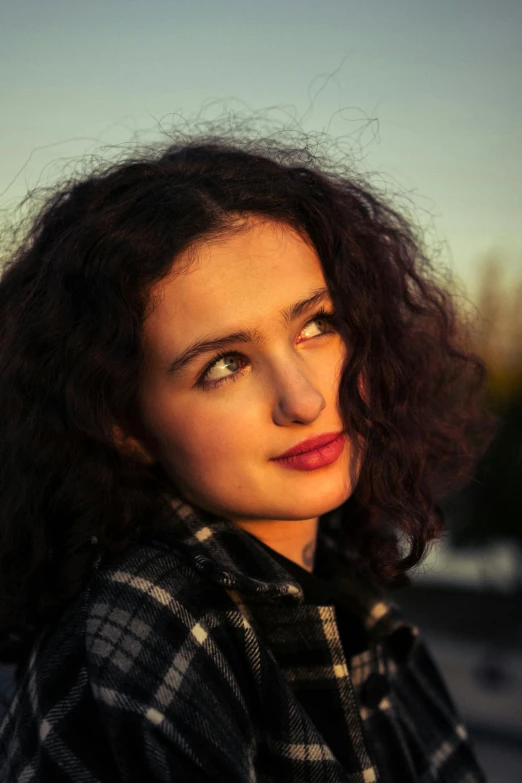 woman with dark curly hair wearing a plaid shirt