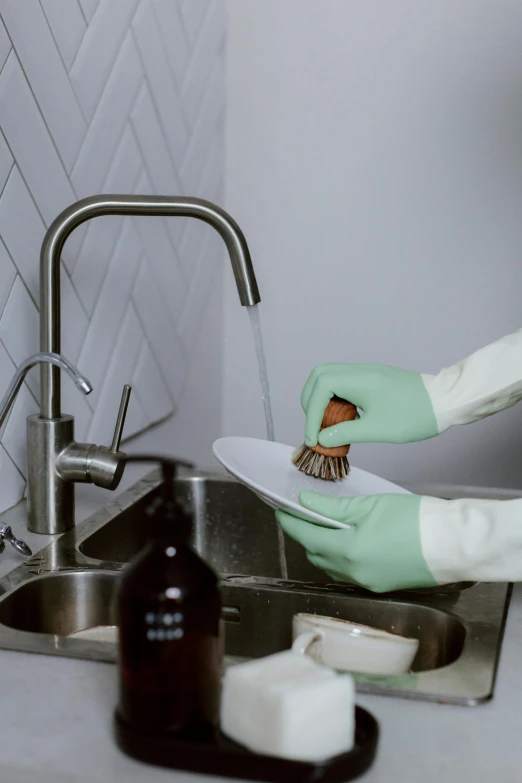 person cleaning dishes in the kitchen using rubber gloves