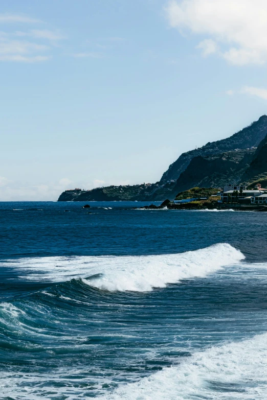 the ocean is very wavy next to a mountain