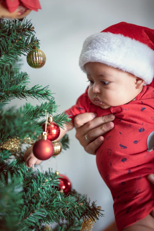 a woman holding a small baby with christmas decorations hanging on it