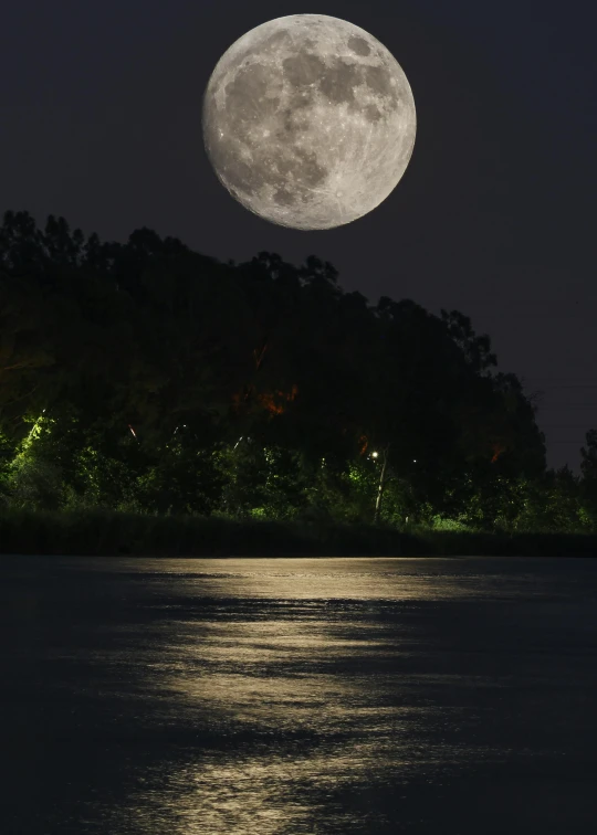 a large full moon is shining above the water