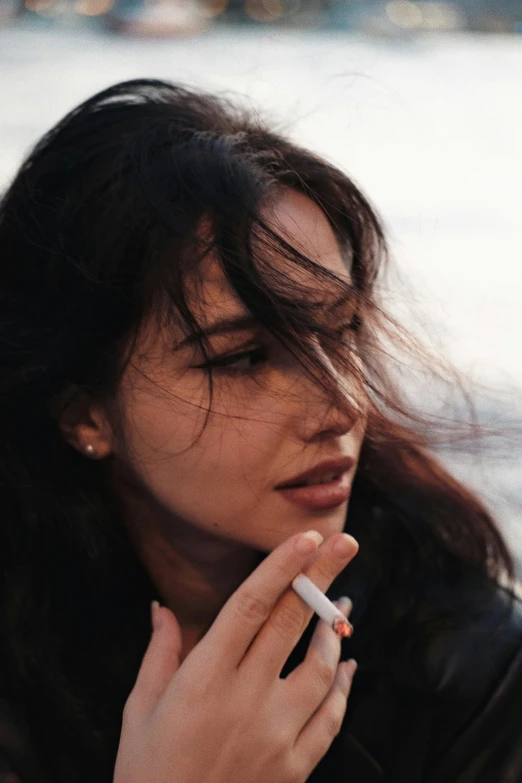 a woman in leather jacket holding a cigarette