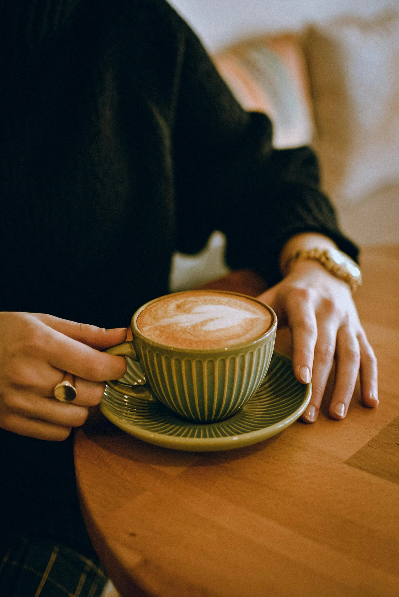 someone sitting at a table holding a cup of coffee