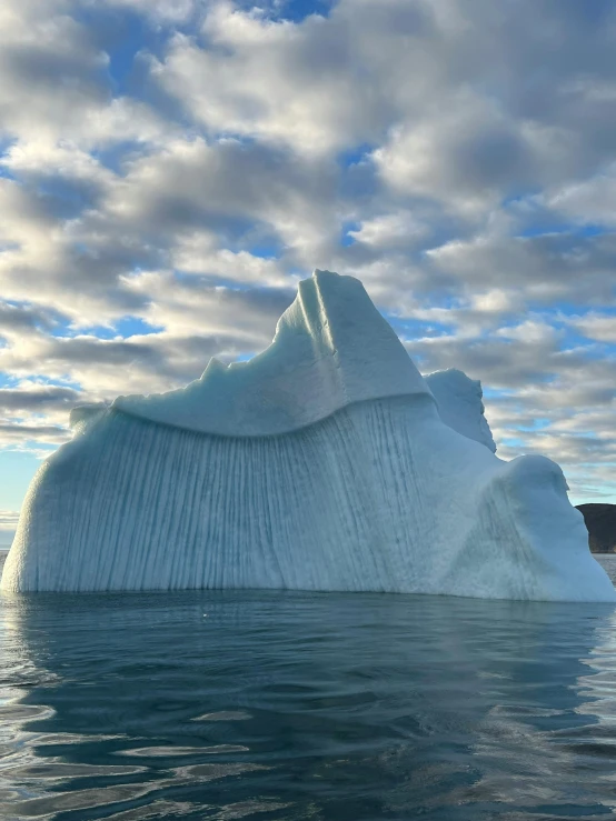 an iceberg floating in the water on a sunny day