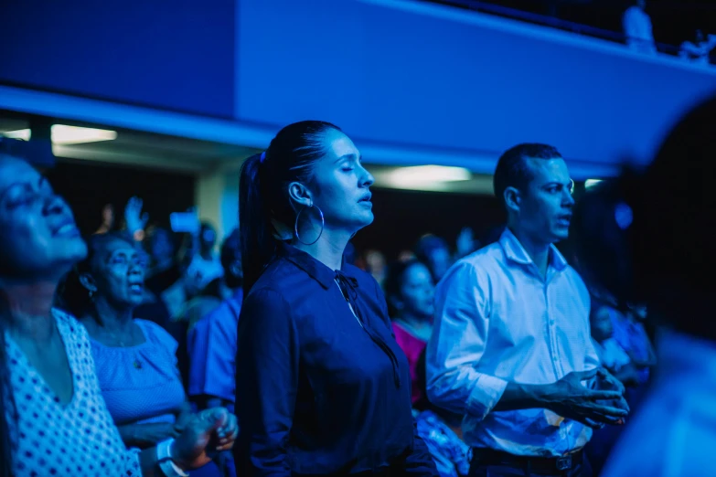 a crowd watching a speaker in a blue light