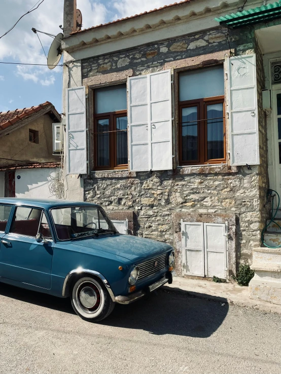 an old blue car parked outside a building