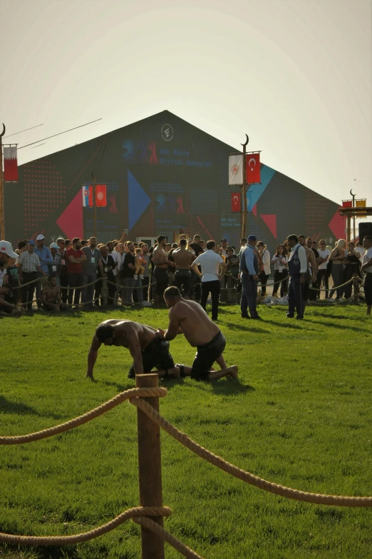 two men with wrestling gloves are on the grass