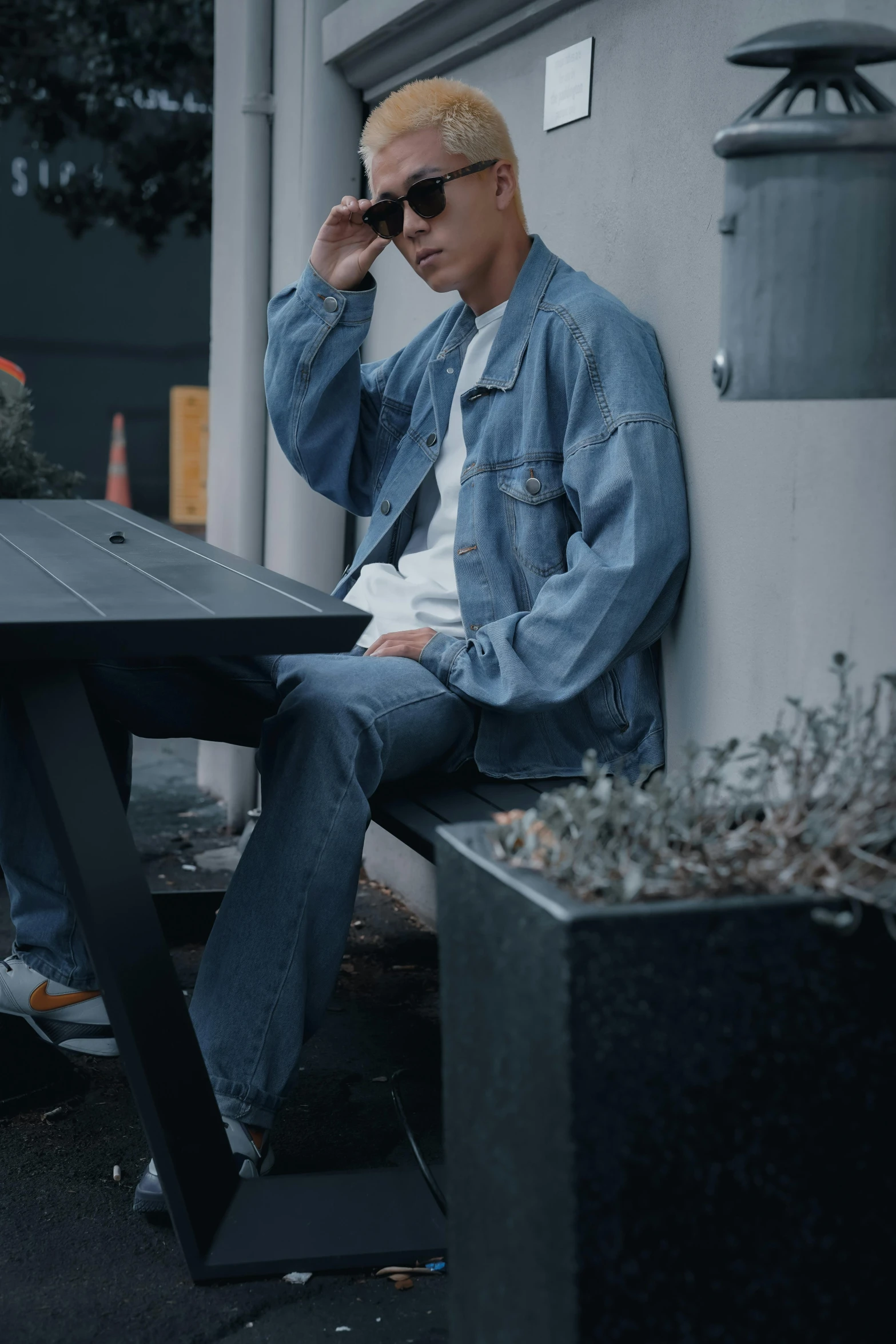 man with blond hair in denim jacket and dark sunglasses