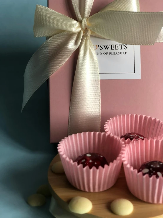 small pink cupcakes next to a box of sweets