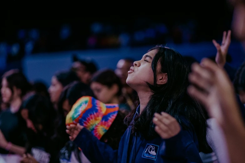 a girl holding her hands up with the crowd clapping