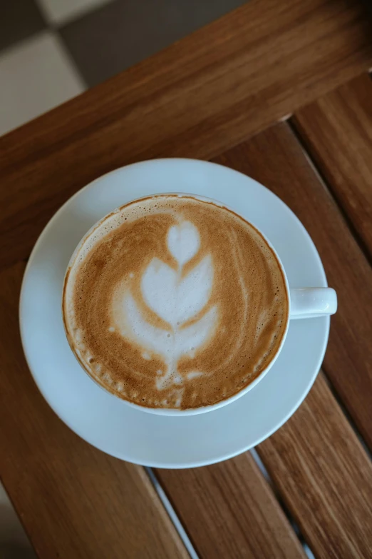 a cappuccino with the shape of a leaf in it on a saucer