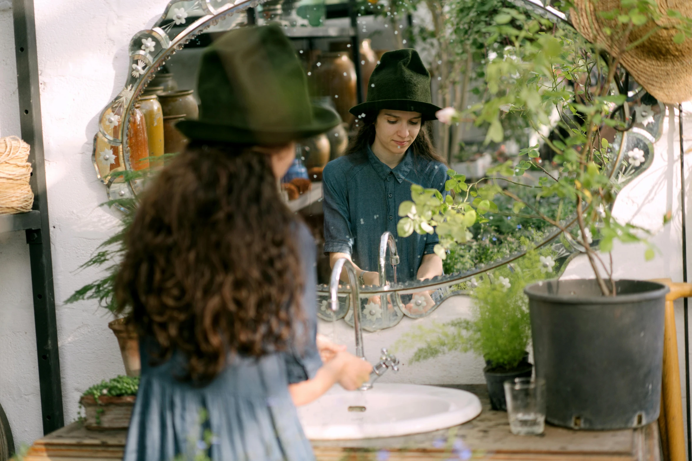 a woman sitting in front of a mirror in front of plants