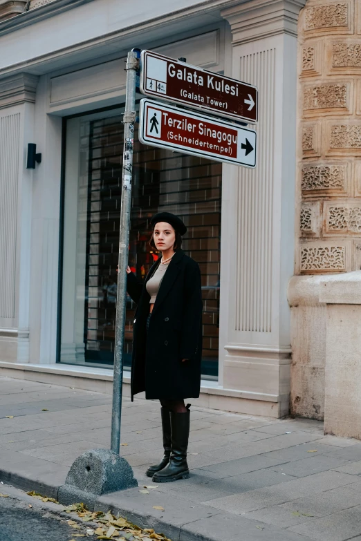 a woman standing at a street corner with a street sign