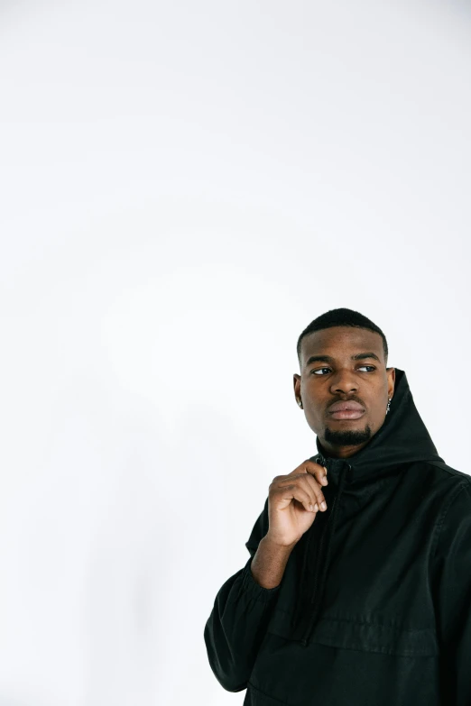 a man with a black shirt standing in front of a white wall