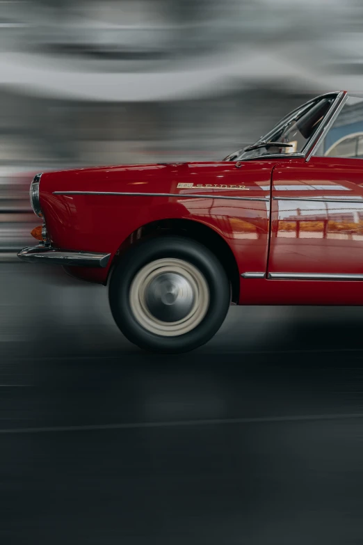 a red car speeding down a street during the day