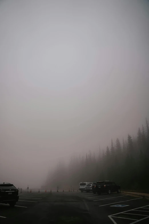 cars and trucks driving down the road in a foggy weather