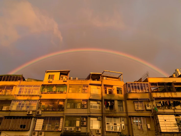 rainbow with clouds over residential area during sunset