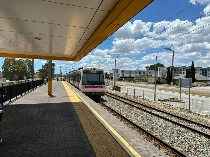 a red train traveling down train tracks near a train station