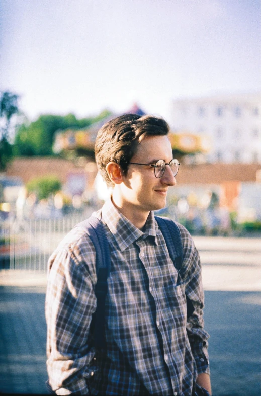 a man wearing glasses and a backpack standing in the street