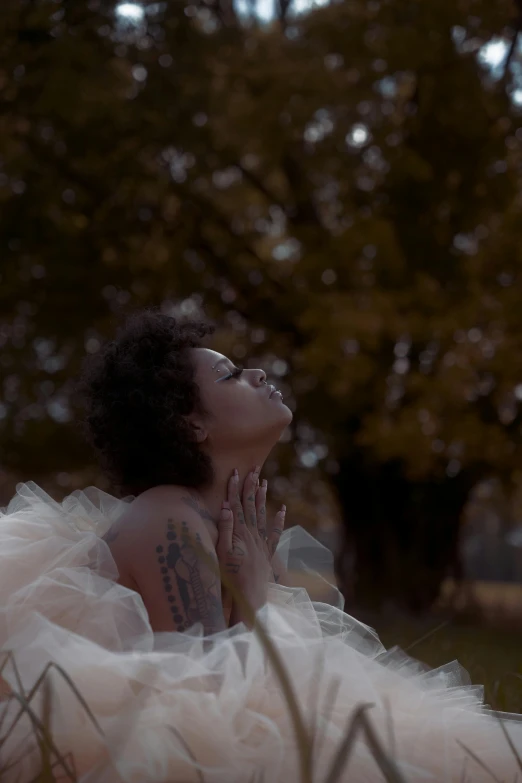 a woman wearing a dress and sunglasses is laying on the grass