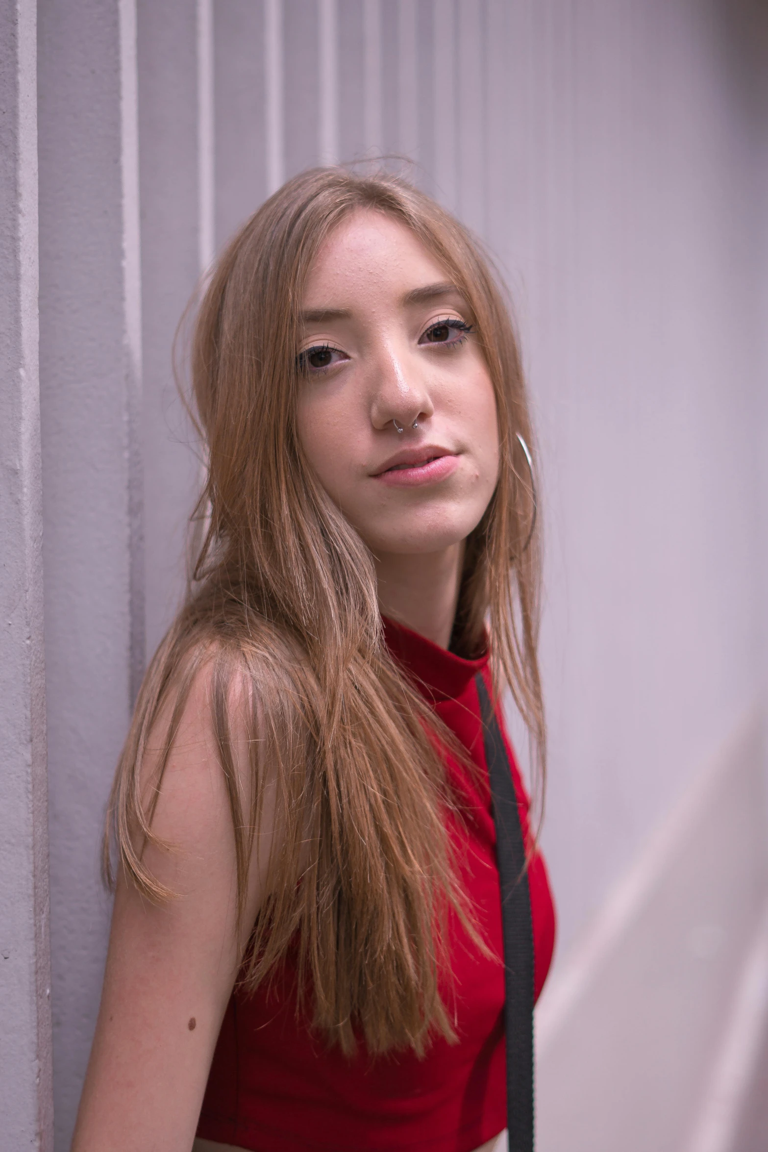 a young woman poses for a portrait in front of a white wall