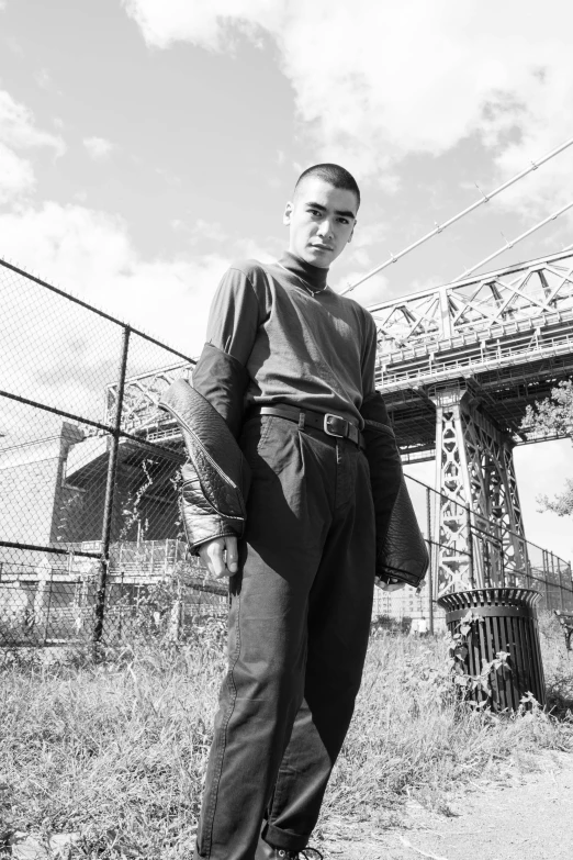 a young man is standing in front of a bridge