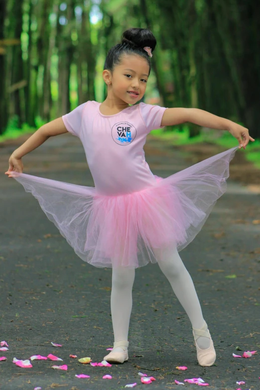  dressed in pink tutu and ballet shoes with one leg raised