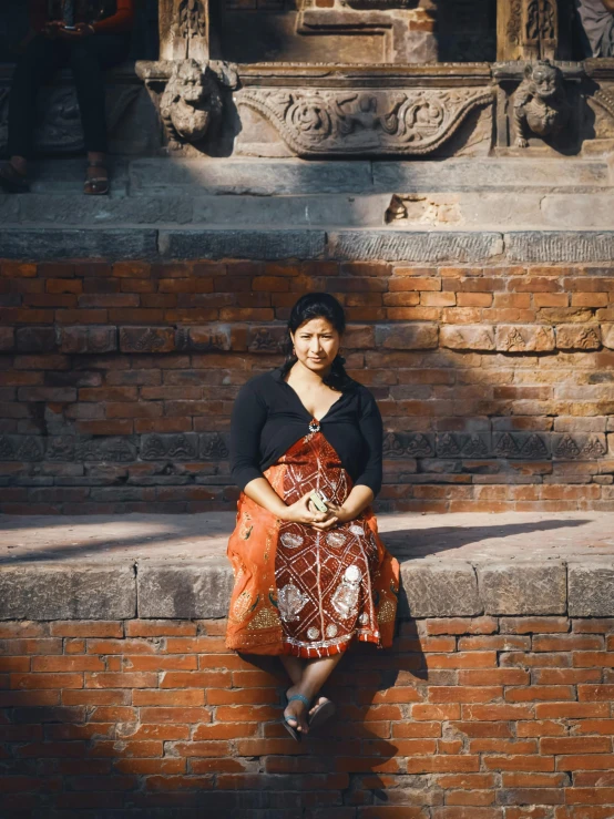 a woman is sitting on a wall with her hand on her hips