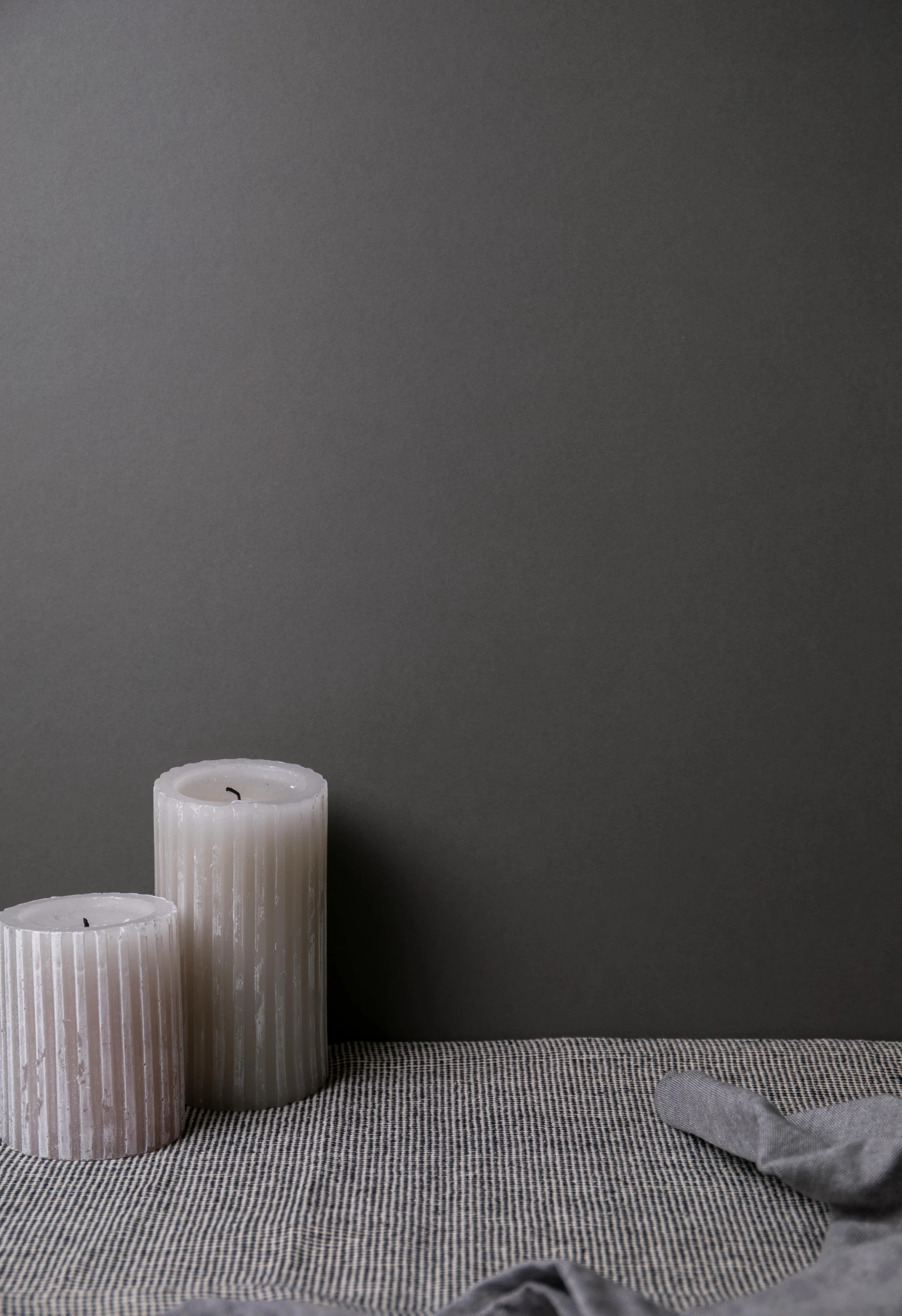 a white candle and another pillar set on a table