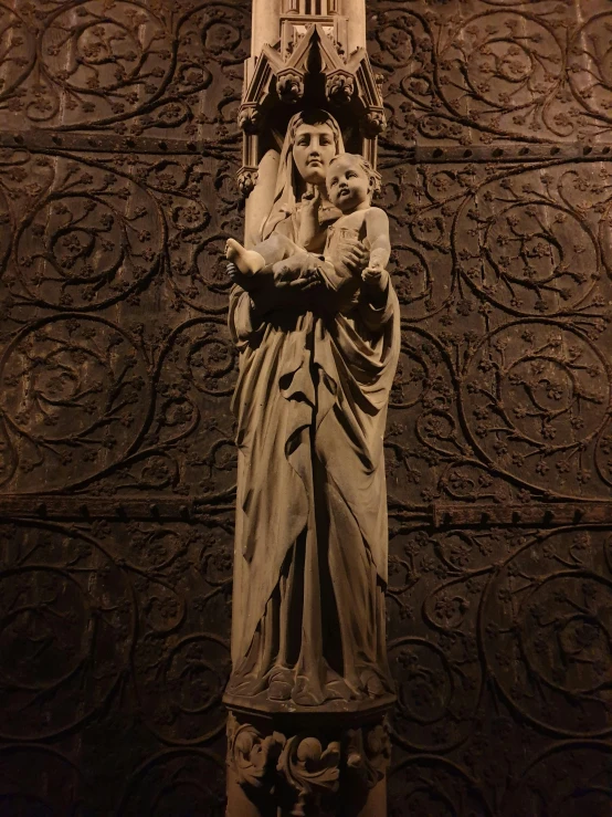 a statue of a woman holding a baby in front of a clock tower