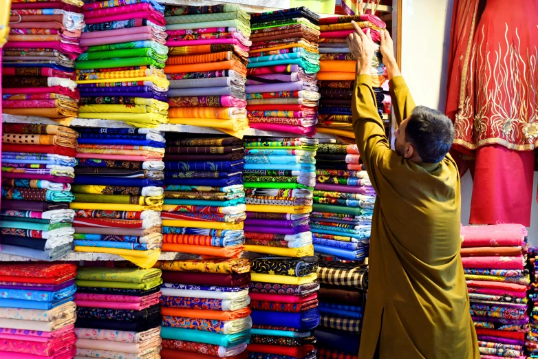 a man is looking through a display of fabrics