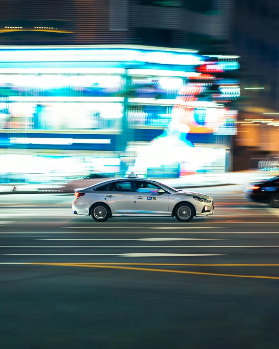 a street with cars stopped at an intersection and buildings lit up in night