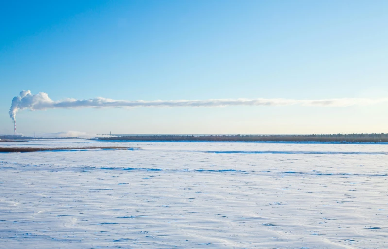 a snowy field with some clouds and blue sky