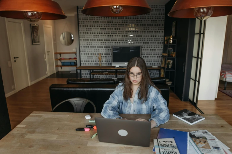 a young woman sitting at a wooden table using a laptop computer