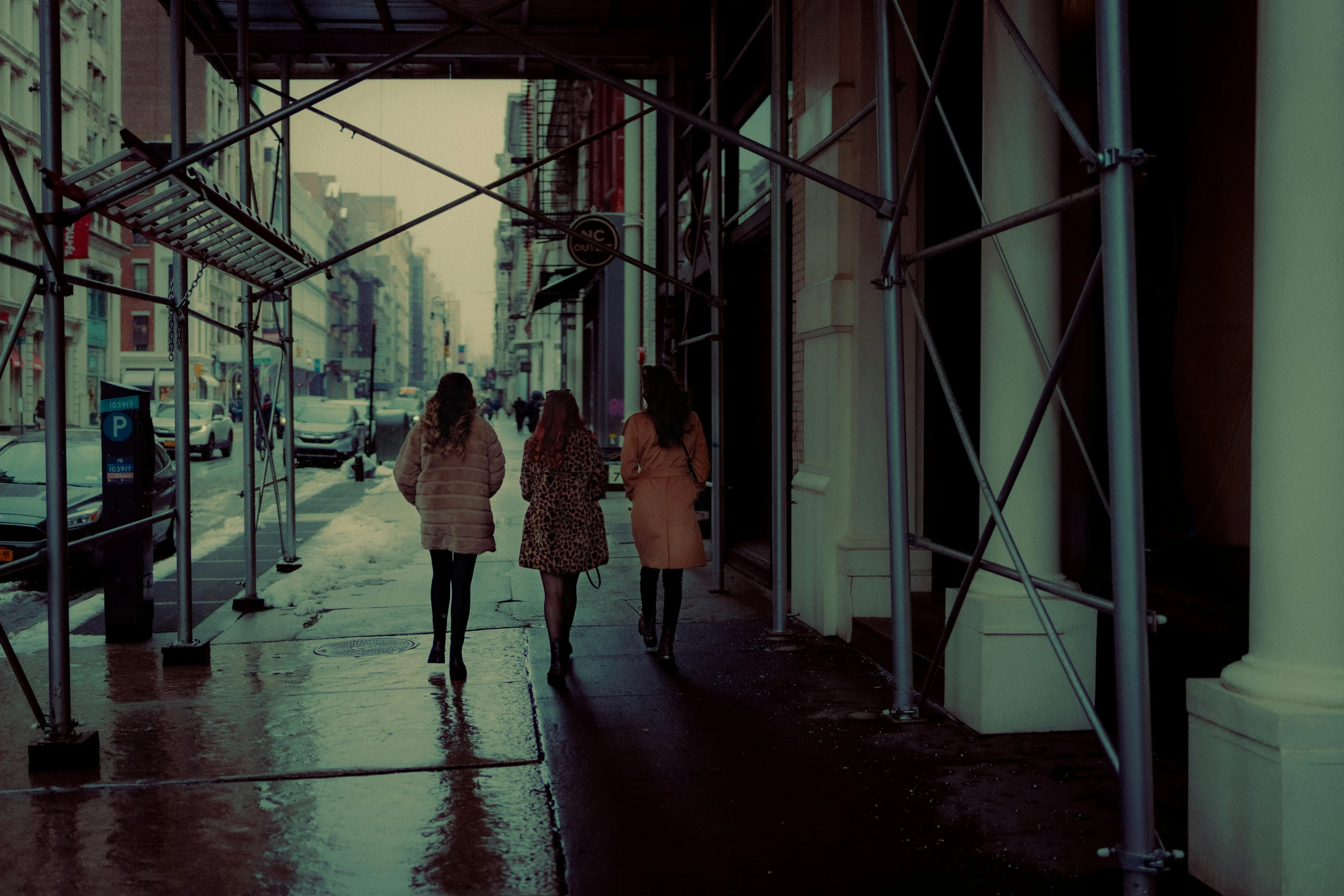 three people walking down the sidewalk in a city