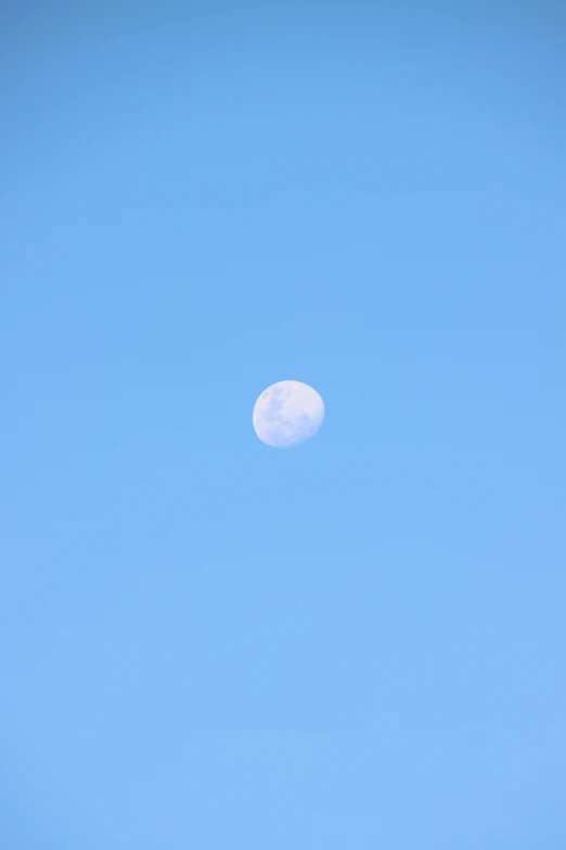 a clear blue sky with the moon seen in it