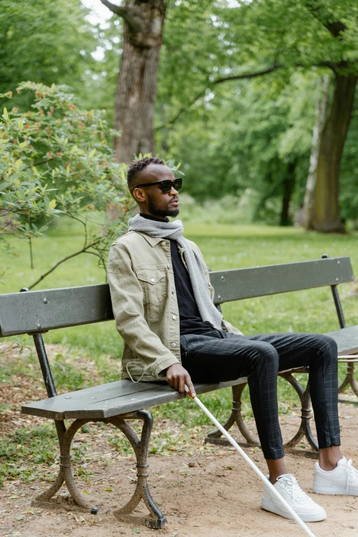 a man sits on a bench with a cane in hand