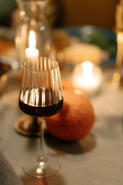 a half - filled wine glass next to lit candles