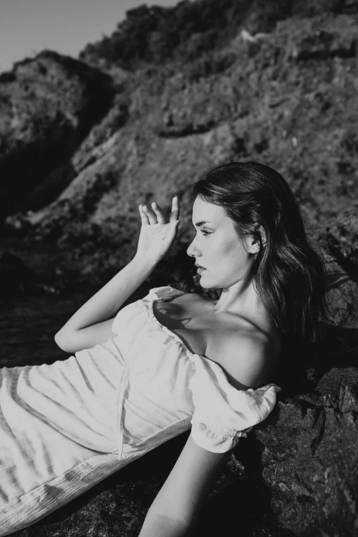 a woman laying on the rocks in a white dress