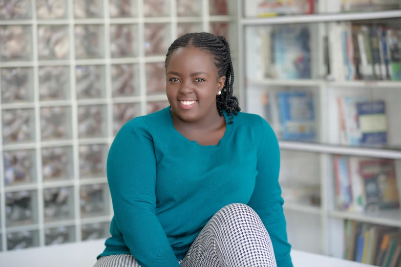 a woman in a turquoise sweater sitting on a counter