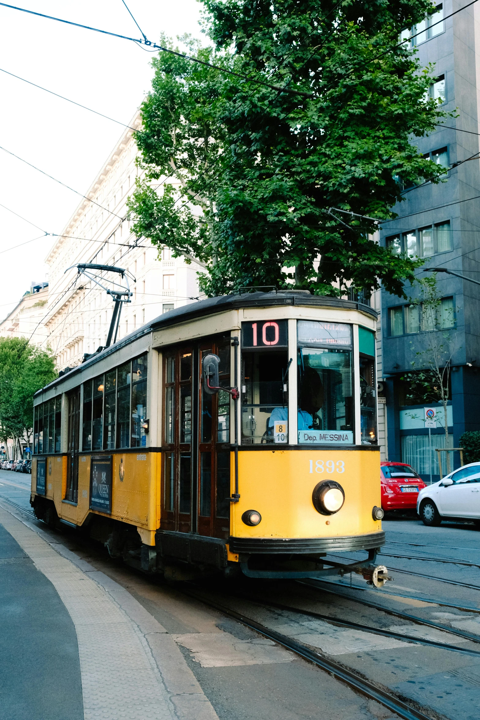 the yellow trolley is traveling down the tracks in the city