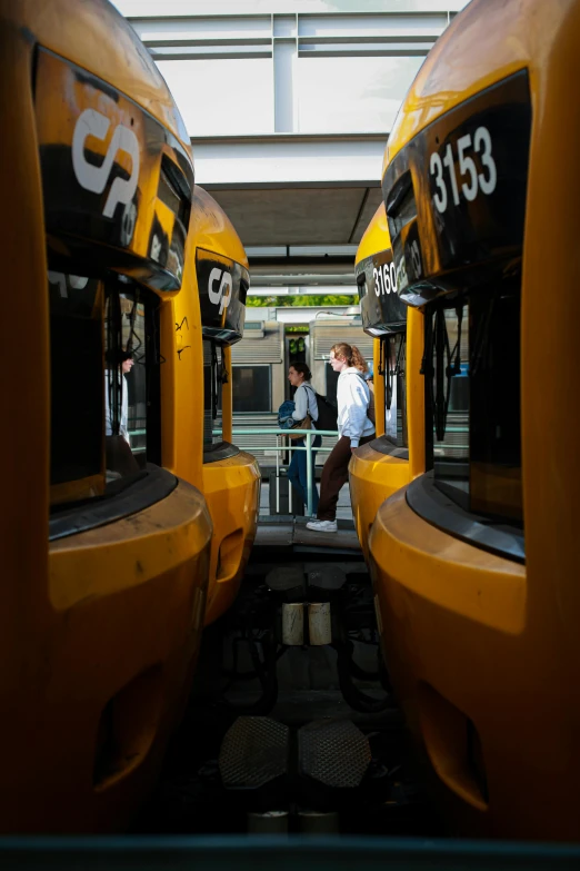 two people are walking toward yellow busses