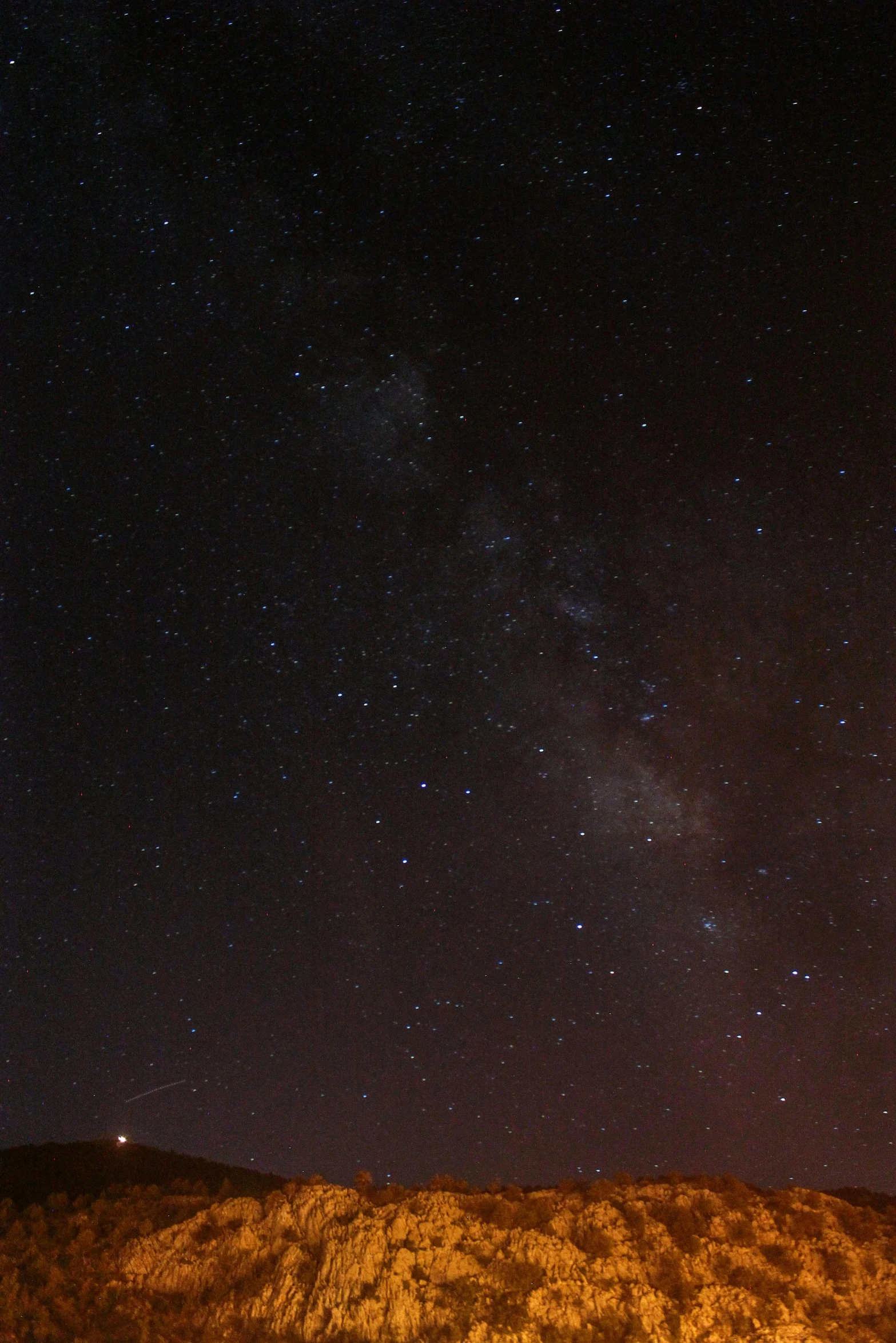 the night sky above a dry hillside and forest