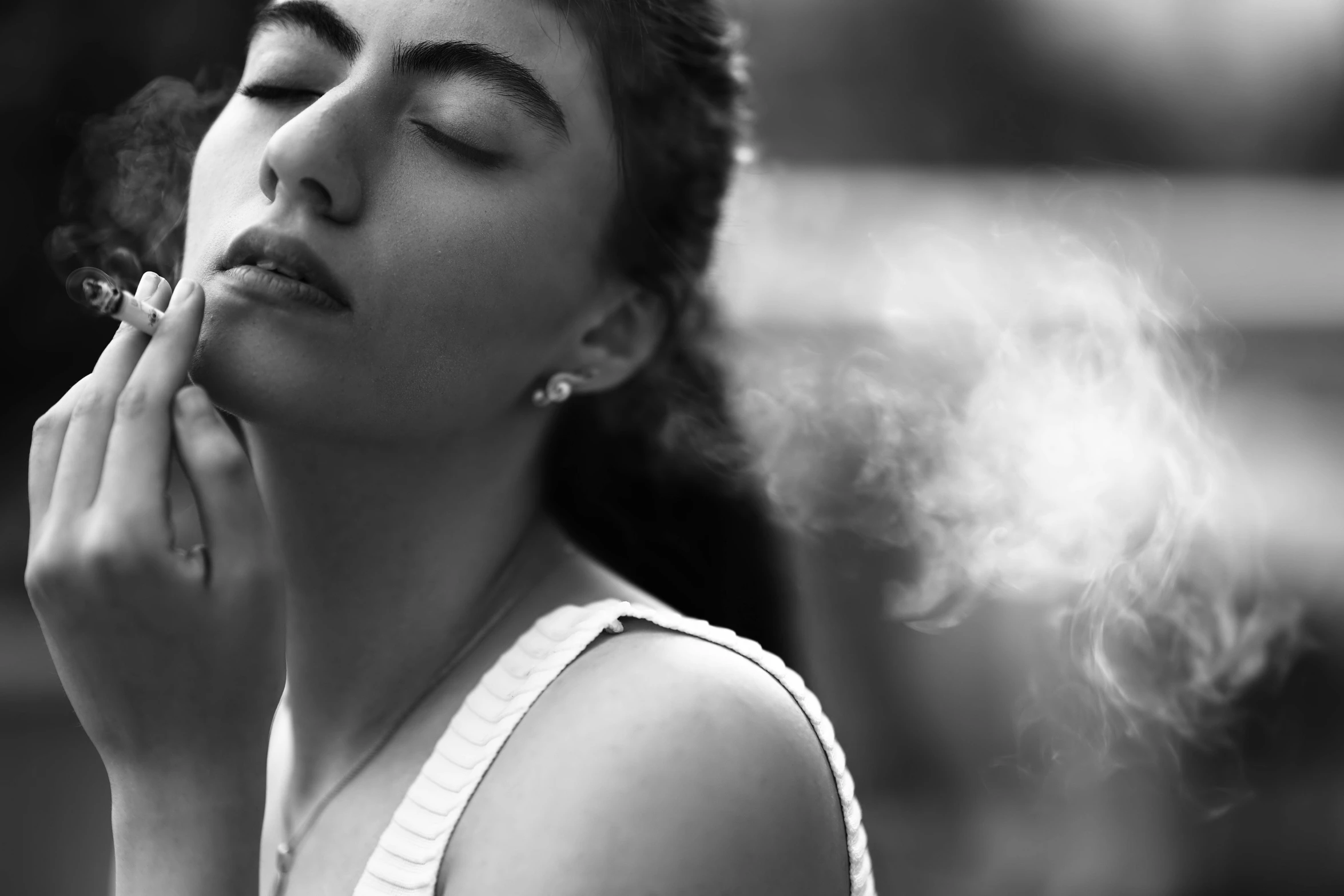 a woman is blowing smoke while sitting down