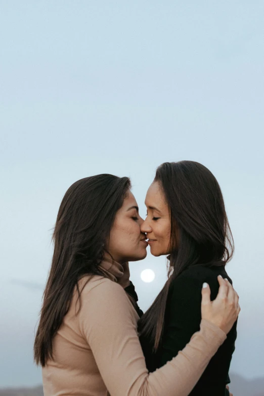 two women hugging each other as they stand next to each other